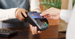 Customer using credit card for payment to owner at cafe restaurant, cashless technology and credit card payment concept