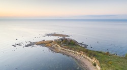 Aerial view to the thin cape badly suffering by coastal erosion and with the abandoned historic coast guard station buildings, nearly collapse to sea