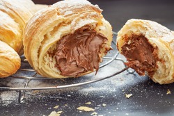 Croissant with chocolate filling on black wooden background