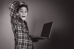 cheerful schoolboy in a shirt using his laptop computer, working on pc at home, online learning self study. Back to School. E-learning, Gamification. Monochrome