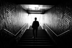 A man walking down the steps through the dark tunnel 
