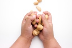 Child's hand holding Peanuts, isolated on a white background.