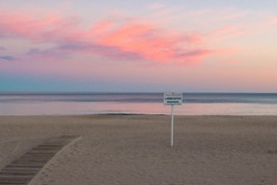 Beach in Villajoyosa, Spain, after sunset, the sign in Spanish reading 