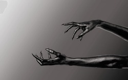 Black Devil Creepy Scary Monster Halloween Hand isolated on a grey background. Concept of murder. Horror Scene with zombie Hand. closeup Black Hands with Long Nails death. monster claw. Copy space.