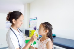 Medical doctor applying medicine inhalation treatment on a little girl with asthma inhalation therapy by the mask of inhaler. Image of a cute kid with respiratory problem or asthma in hospital.