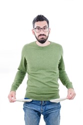 Portrait of frustrated worried brunette man with beard in casual green sweater turning out empty pockets showing I have no money gesture, bankrupt. indoor studio shot isolated on white background