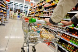 A Shopper Pushes a Trolley along a Supermarket Aisle - Image has a Shallow Depth of Field