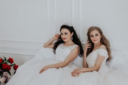 Portrait of two young women in wedding dresses in White Hall