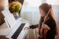 Home lesson for playing the violin and piano. The idea of activities for children during quarantine. Music concept