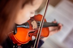 Home lesson for a girl playing the violin. The idea of activities for children during quarantine. Music concept. Selective focus