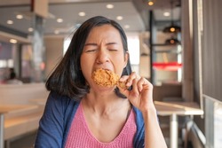 Asian beautiful woman enjoy eating with fried chicken. hungry woman looking, eating fried chicken, concept of delicious food, health care, eating habit, yummy fried chicken.