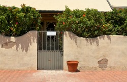 Metal gate entryway set in an adobe wall on a bright sunny day.