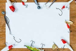 A blank sheet of paper for your text on the topic of fishing. On a wooden table. The idea: how to catch, trophy, fish. Fishing gear, hooks and baits on a light wooden background.