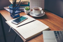 Diary and notebook for Planner to plan agenda, reminder, timetable, daily appointment, management on table. Calender, laptop, smartphone and cup of coffee place on office desk. work online at home