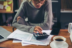 Season to pay Tax and Budget planning concept. Business woman calculating annual tax and using mobile phone. Calendar 2021 and personal income tax form placed on home office desk.