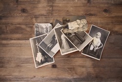 old vintage monochrome photographs are scattered on a wooden table, photographs of his and his sisters, pictures taken in 1964, concept of genealogy, the memory of ancestors, family ties, memories 