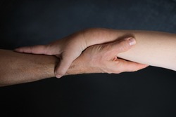 male and female hands together on black background, old skin with wrinkles and veins, concept of health, age-related changes, love, tender relationship of a couple in llife
