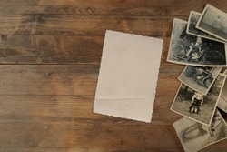stack of old vintage monochrome photographs 1950 on photographic paper on natural wood background, concept of genealogy, memory of ancestors, family tree, nostalgia, childhood, remembering
