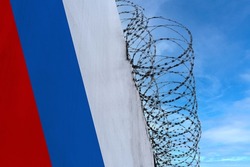 national flag of Russia on concrete wall, barbed wire fence, concept of prison, symbol of police state, territory border, totalitarian regime, restriction of rights and freedoms of citizens