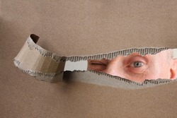 blank cardboard form, craft paper, hole with Human eye, mature man, senior 60 years old looking straight, covertly is following, concept of secrecy, spying, Surveillance System, face Recognition