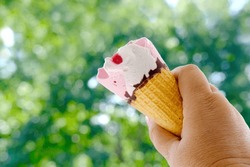 female hand close-up holds, going eat cold ice cream cone, strawberry dessert with fruit jam and chocolate, appetizing eating, happy childhood concept, children's delicacy, healthy and unhealthy food