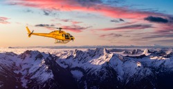 Yellow Helicopter flying over the Rocky Mountains. Dramatic Sunrise. Aerial Landscape from British Columbia, Canada near Vancouver. Composite. Canadian Panoramic Nature Background