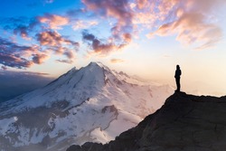 Adventure, Explore and Lifestyle Concept Composite. Adventurous Man Hiker on top of a Steep Rocky Cliff. Sunset or Sunrise. Landscape Taken from Washington, USA.
