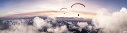 Adventure Composite Image of Paraglider Flying up high in the Rocky Mountains. Sunny Sunset Sky. Aerial Background from British Columbia, Canada. Extreme Sport Concept. Panorama