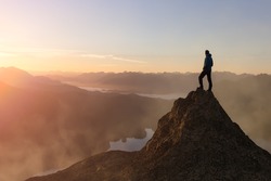 Adventure Composite. Adventurous Adult Man hiking on top of a mountain. Colorful Sunset or Sunrise Sky. 3D Rocky Peak. Aerial Background Landscape from Vancouver Island, British Columbia, Canada.