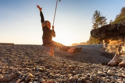Adventurous White Caucasian Woman on a swing at Sandcut Beach on the West Coast of Pacific Ocean. Summer Sunny Sunset. Canadian Nature. Located near Victoria, Vancouver Island, BC, Canada.
