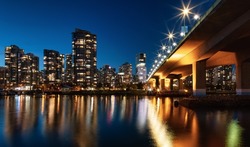 Cambie Bridge in False Creek with modern city buildings at night after sunset. Downtown Vancouver Cityscape, British Columbia, Canada.