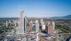 Aerial view of a big construction site at a mall with skytrain and apartment buildings in the vicinity. Taken in Burnaby, Vancouver City, British Columbia, Canada.