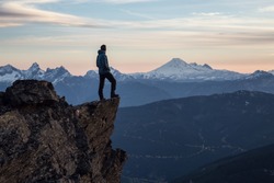 Adventurous man is standing on top of the mountain and enjoying the beautiful view during a vibrant sunset. Taken on top of Cheam Peak in Chilliwack, East of Vancouver, BC, Canada.