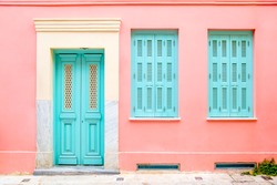 Colorful turquoise blue door and windows in a pink wall.