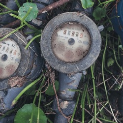 Grass had grown up around the water meters.  Despite having an aged, dirty, and dusty appearance, it still functions properly.