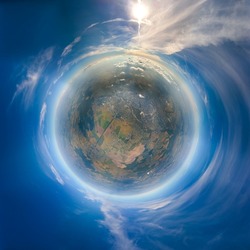 Aerial view from airplane window at high altitude of little planet earth covered with white thin layer of misty haze and distant clouds at sunset