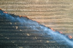 Aerial view of grassland field burning with red fire during dry season. Natural disaster and climate change concept