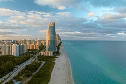 High angle view of Sunny Isles Beach city at sunset with expensive highrise hotels and condo buildings over beachfront on Atlantic shore. American tourism infrastructure in coastal southern Florida
