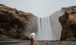 Girl who proudly standing with his arms raised in front of water wall of mighty waterfall.Women riding a swing.