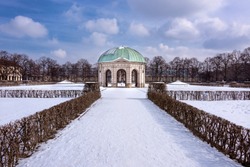 Germany, Bavaria, Munich, Hofgarten: Winter scene of famous Court Garden (Schlossgarten) and Temple of Diana (Dianatempel) in the German city center of the Bavarian capital with white snow, blue sky.