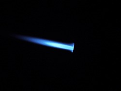 The glow of a gas lighter torch in the dark. Close-up.