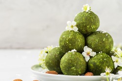 Raw vegan energy balls made of matcha tea, dates and nuts with spring blossom flowers. Food styling. Healthy vegan dessert. close up with copy space