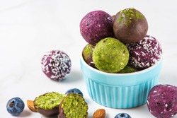 Raw energy balls with acai berry powder and matcha tea in chocolate glaze on white table. Healthy sweet snack. close up
