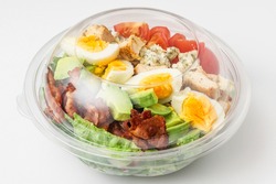 Healthy cobb salad in plastic package for take away or food delivery on white background. close up. keto diet