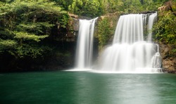 Klong Chao waterfall cascades serenely into the tranquil green pool below, in the interior of the island of Koh Kood, Thailand.
