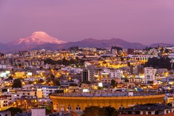 Quito city at night in modern district with the Cayambe volcano and bullfighting arena, Ecuador.