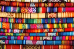 Andes textile fabric pile on Cusco handicraft market, Peru.