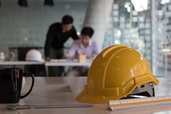Close up view of engineer worktable with safety helmet, copy space and measuring tool on white desk in glass partition office room