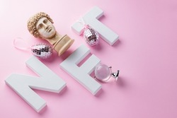 NFT (Non-Fungible token) and antique statue on a pink background. Crypto art concept with NFT, plaster bust, mirror eggs and globe. Technology selling unique collectibles