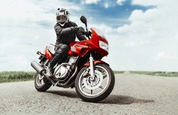 A man rides a motorcycle on the highway to the camera. A man on a red motorcycle makes a turn in front of the camera